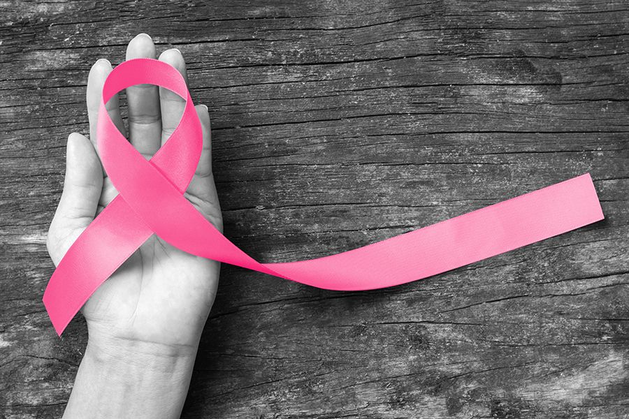 a hand holding a pink breast cancer ribbon
